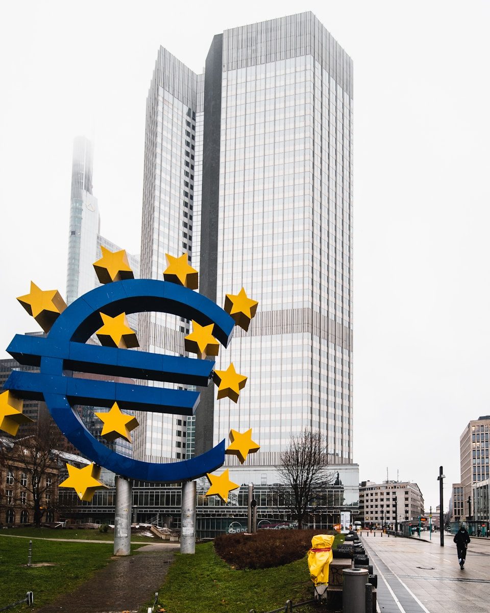 a large blue and yellow euro sign in front of a tall building